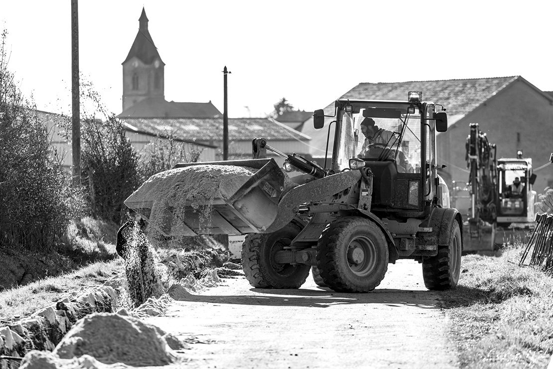 Pelle de chantier remplisant un trou avec du sable